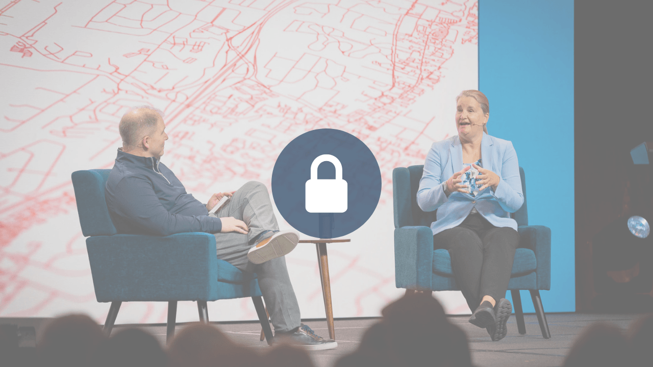 Locked session video: a man and a woman, John Stonestreet and Jean Twenge, Ph.D., seated in blue armchairs on a conference stage mid-conversation, with a red street-map backdrop; a padlock icon overlays the center.